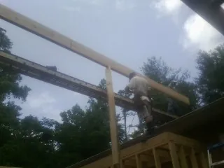 Carpenter setting a ridge beam over a new addition frame — Ice Dam Removal by Roofing Brothers in New Raymer