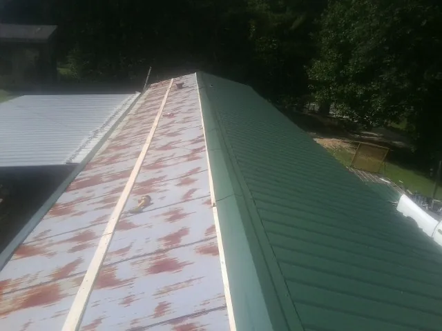 Old rusted panels beside newly installed green metal roofing — Wind Damage Roof Repair by Roofing Brothers in New Raymer
