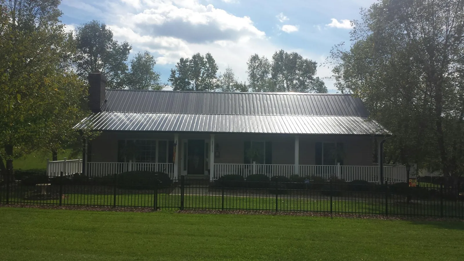 Gray metal roof on a brick ranch with a full width front porch — Gutter Guard Installation work by our crew in New Raymer