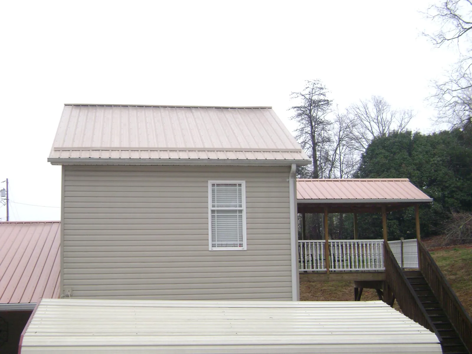 Tan metal roofs on a two story addition and attached porch, from a Roof Replacement job in New Raymer