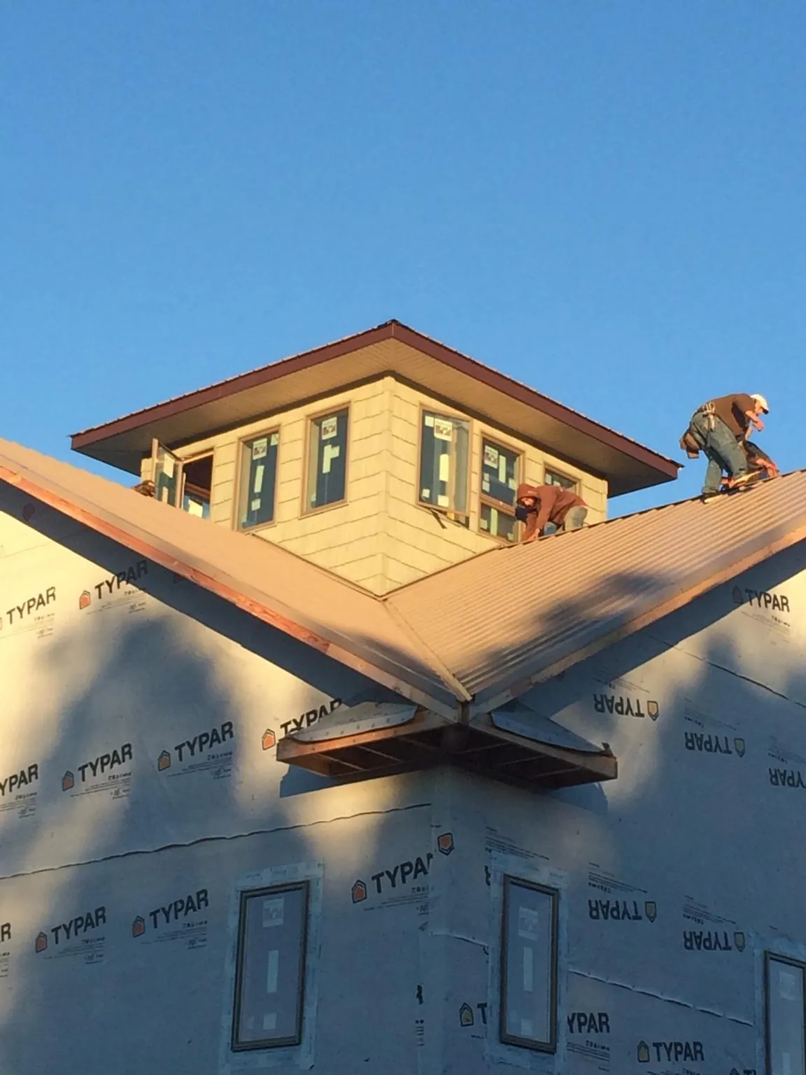 Roofers working around a rooftop cupola on a new metal roof at sunset — Roof Waterproofing in New Raymer by Roofing Brothers